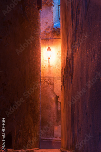 Warm glow of single street light at end of small French town narrow lane