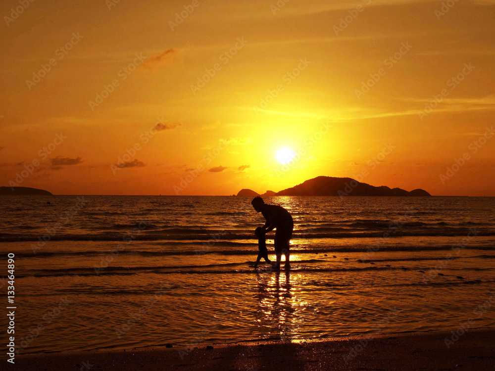 father and son on the beach in vacation in sunset