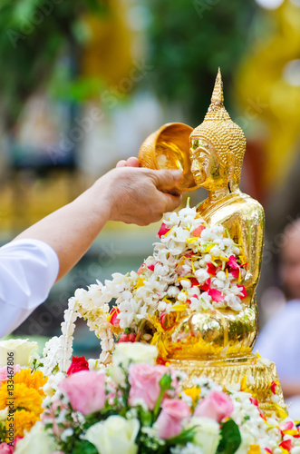people showering buddha statue