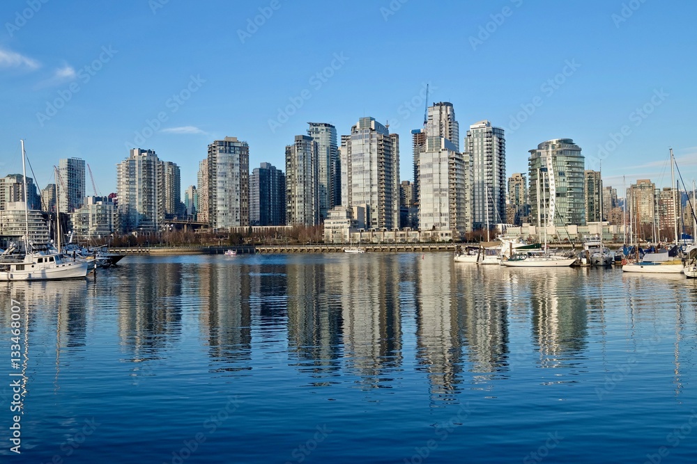 City view and reflection in calm water. False Creek from Granville Island. Yaletown. Vancouver. British Columbica. Canada.