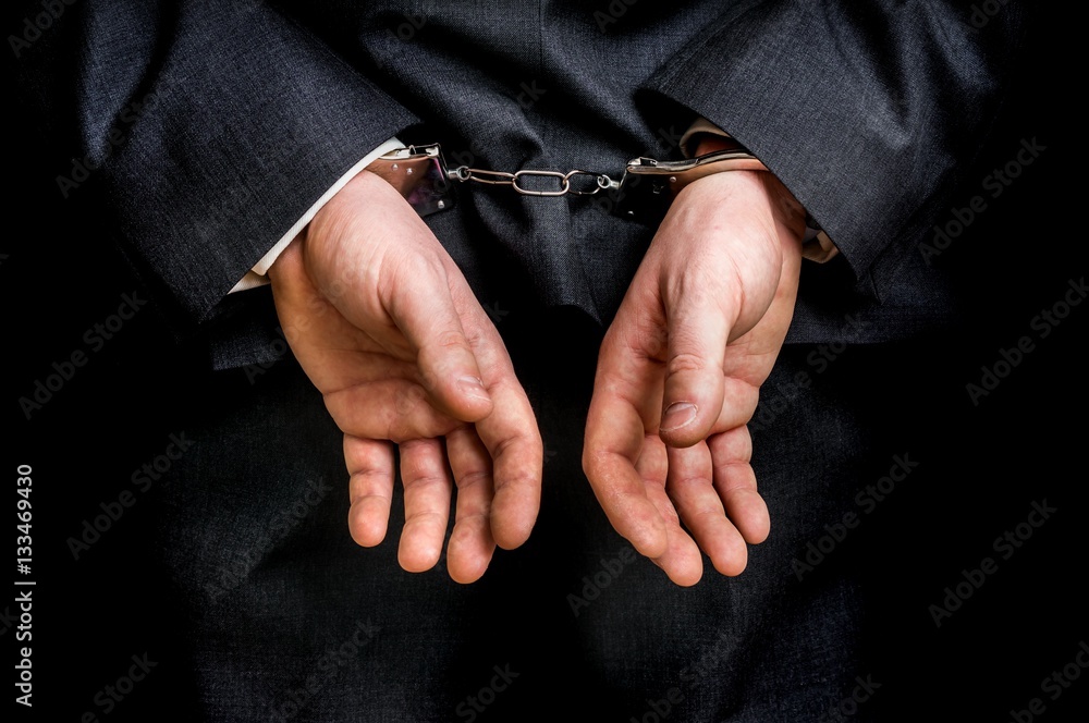 Arrested businessman in handcuffs with hands behind back Arrested businessman in handcuffs with hands behind back