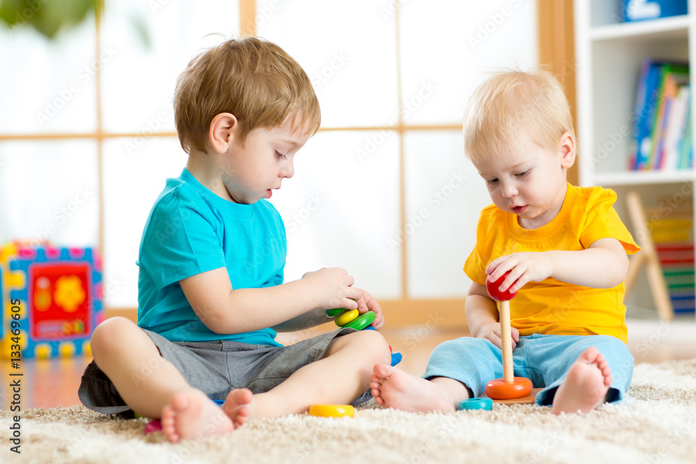 Children play with educational toys in preschool or kindergarten. Toddler kid and baby build pyramid toys at home or daycare. Children play with educational toys in preschool or kindergarten. Toddler kid and baby build pyramid toys at home or daycare.