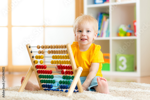 Preschooler baby learns to count. Cute child playing with abacus toy. Little boy having fun indoors at kindergarten, playschool, home or daycare centre. Educational concept for preschool kids.