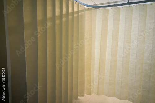 Hanging dividing curtain in a hospital ward. Folding room divider. Privacy curtain with multiple folds. Medical curtain hanging from a railing in a hospital room.