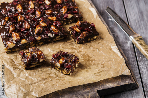 Chocolate and biscuit cake with Brazil nuts and dried cranberries sliced into pieces. Selective focus 