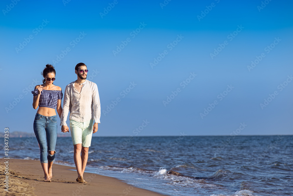 Couple walking on beach. Young happy interracial couple walking on beach.