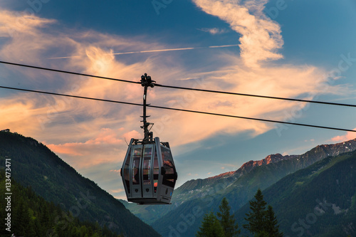 A solitary gondola hangs from a cable in Chamonix, France during sunset
