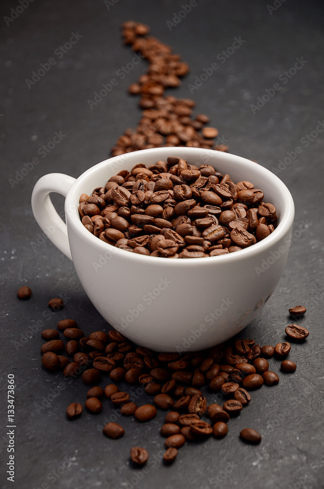 Fototapeta premium Natural organic roasted coffee beans in white cup on black background, selective focus