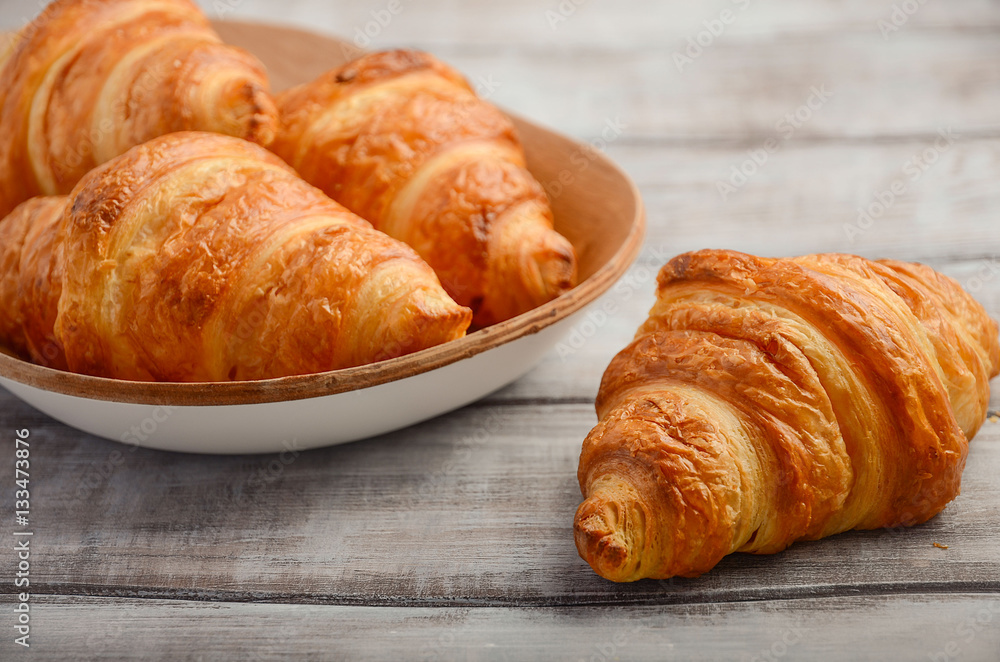Fresh Croissants on rustic wooden background.