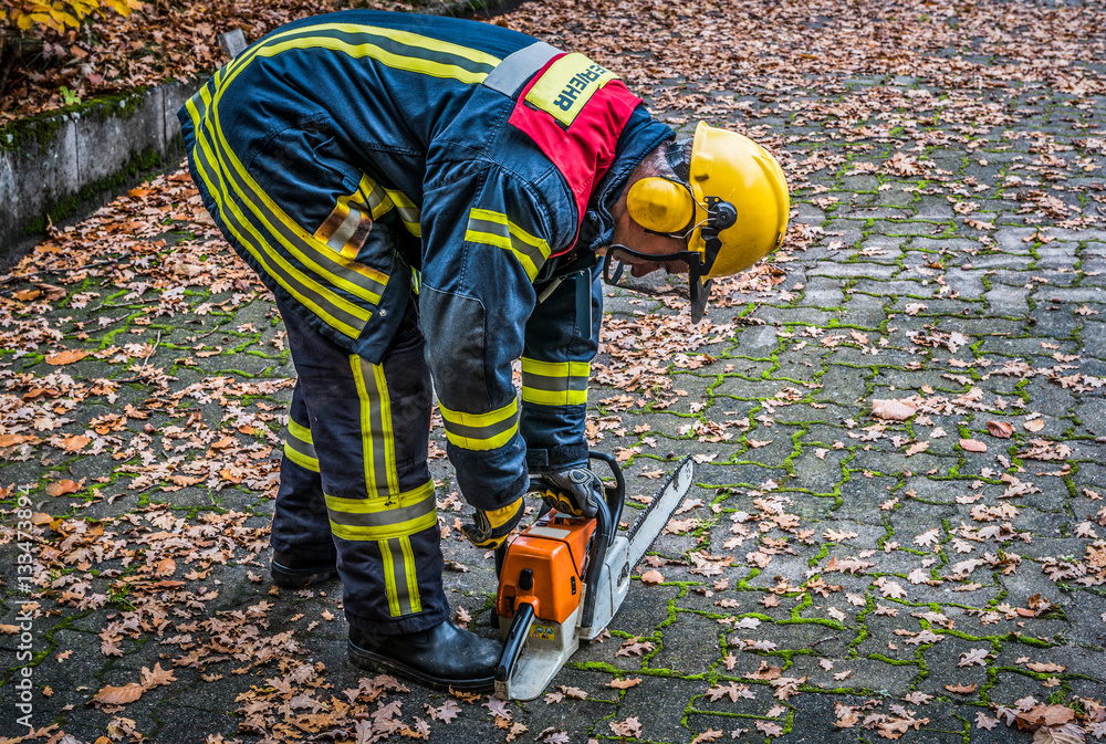 Fototapeta premium HDR - Feuerwehrmann im Einsatz mit Kettensäge