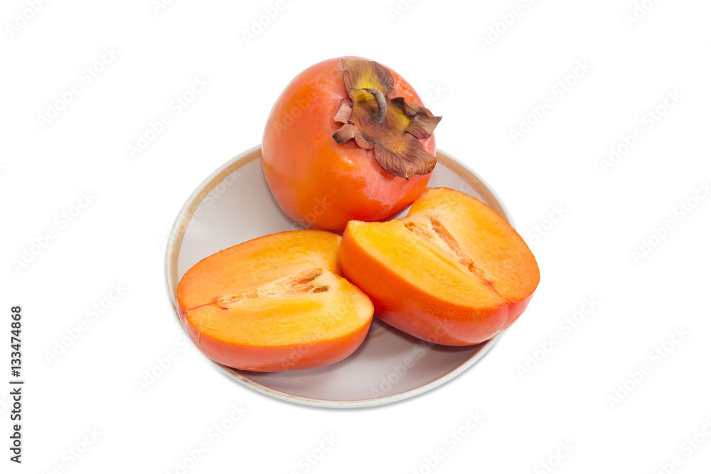 One whole and cut in half of persimmon on saucer