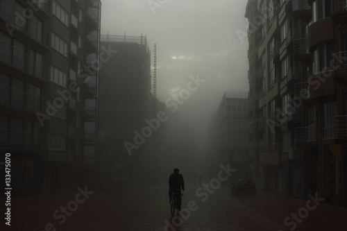 Cyclist on a street in foggy city