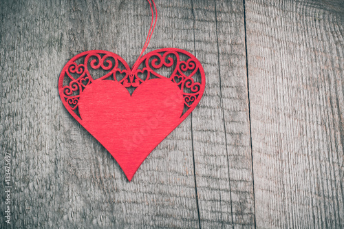 Valentine's card. Wooden red carved heart over wooden table background with copy space.