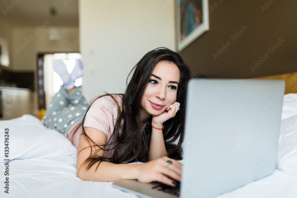 Young girl lying at home in her bed and use laptop Young girl lying at home in her bed and use laptop