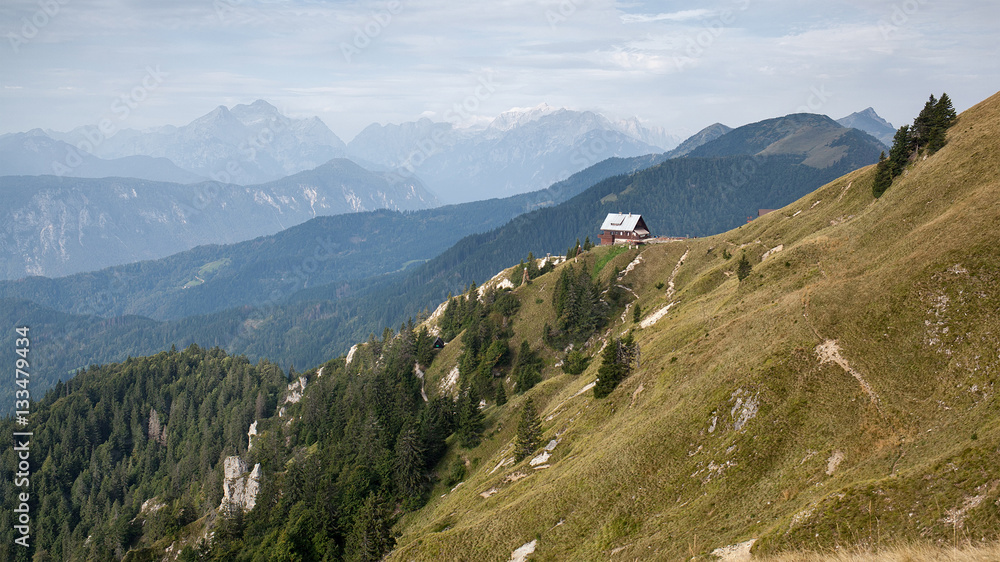 Mountain landscape with a mountain hut on the nearby ridge. Koca na Golici in Karavanke mountains in Slovenia.
