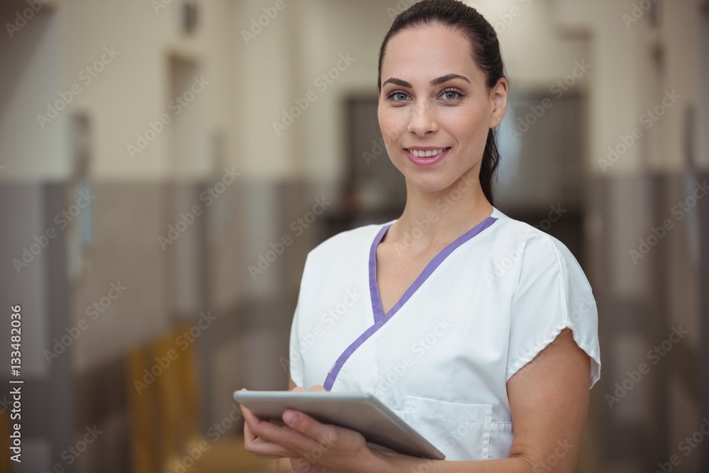 Portrait of female nurse using digital tablet in corridor Portrait of female nurse using digital tablet in corridor