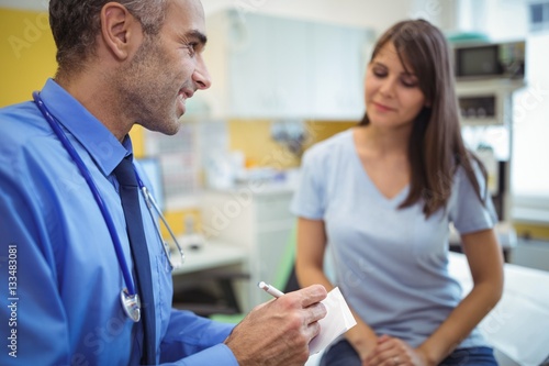 Doctor interacting writing on paper while consulting patient