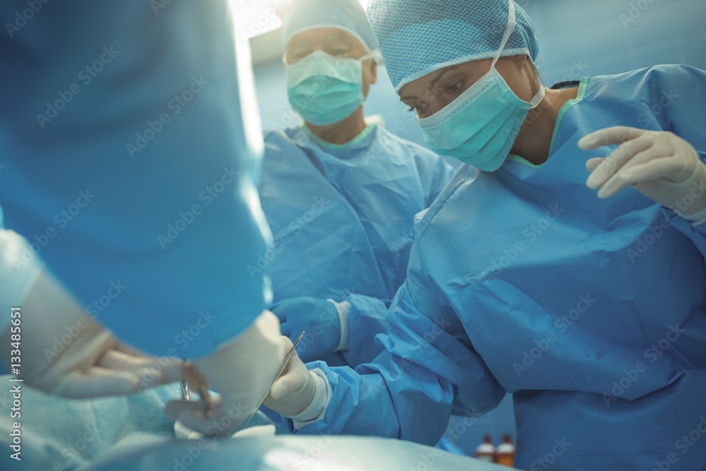 Team of surgeons performing operation in operation theater Team of surgeons performing operation in operation theater