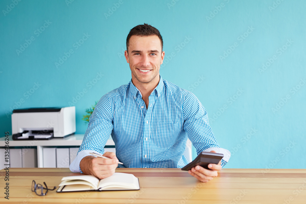 Man calculates tax at desk in office Man calculates tax at desk in office