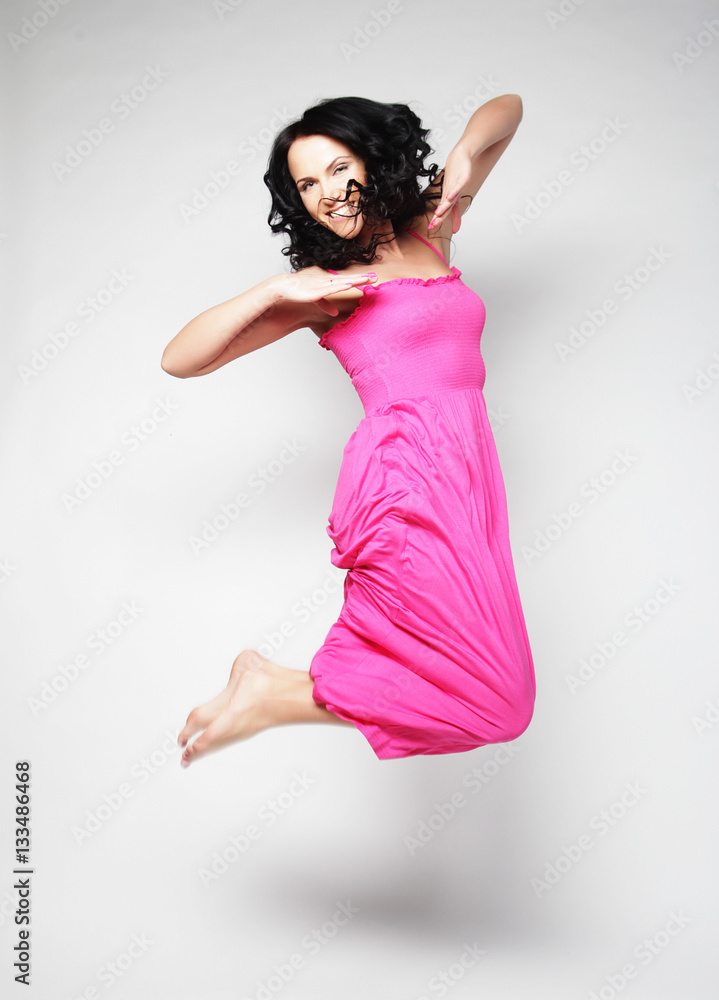 Jumping woman. Happy emotional girl wearing pink dress.  