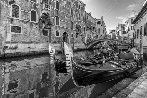 Black and white view of typical traditional gondolas parked in a Venetian canal, Fondamenta dei Preti, Venice, Italy