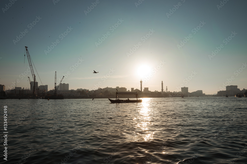 silhouette of a boat floats on the sea channel of Dubai on the background of the setting sun, the long-range plan, Dubai