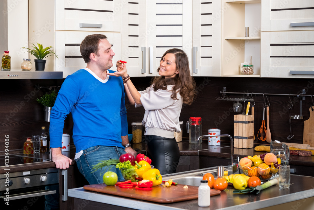 Young couple having fun in the kitchen preparing dinner