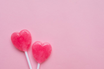 two Pink Valentine's day heart shape lollipop candy on empty pastel pink paper background. Love Concept. Knolling top view. Minimalism colorful hipster style.