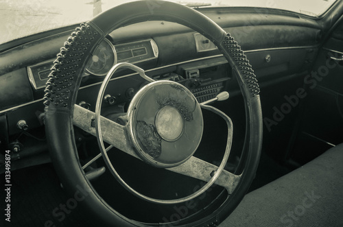 The panel of an old antique car, focused on the steering wheel. Cars that take us back to another time when the driving panel were simpler.