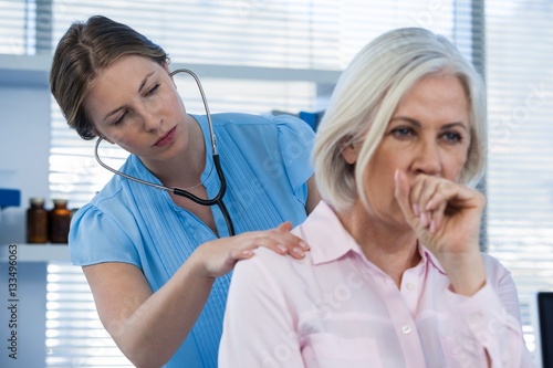 Doctor examining coughing patient photo