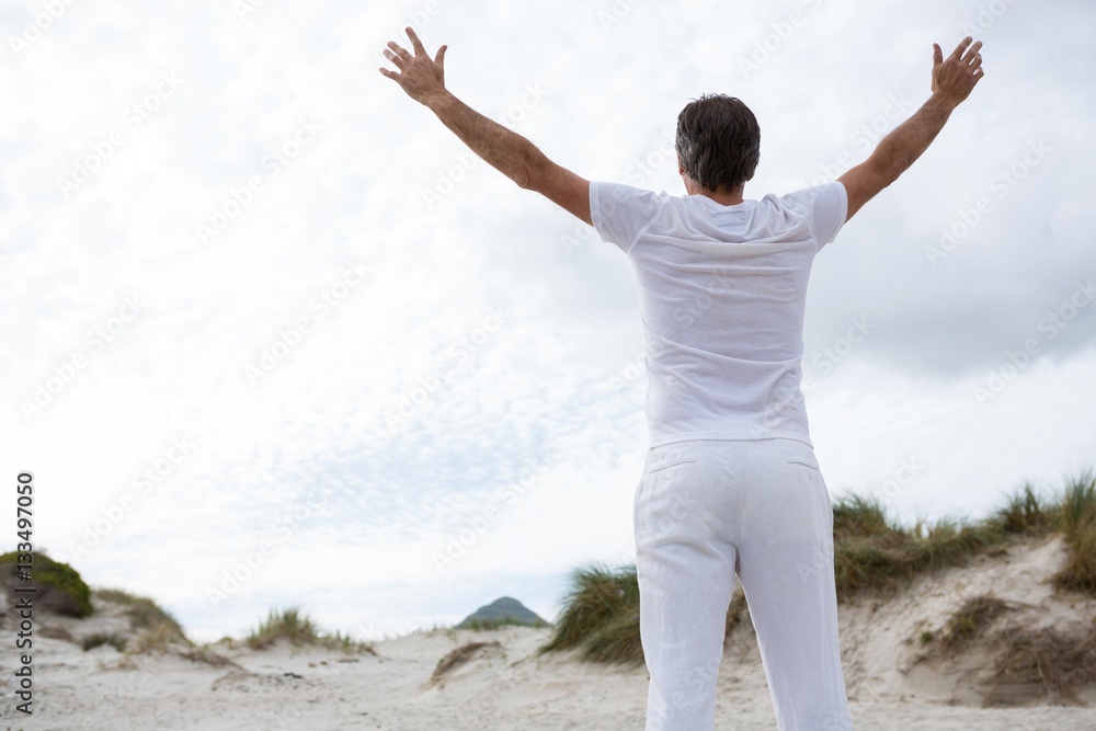 Rear view of man standing with arms outstretched on beach Rear view of man standing with arms outstretched on beach