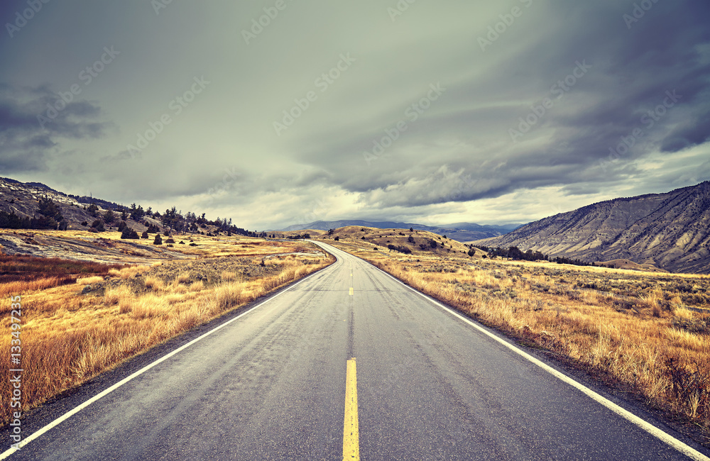 Vintage toned scenic road with stormy clouds, travel concept