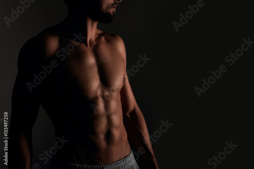 Handsome muscular man posing on black background