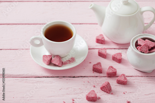 Granulated pink sugar  in the shape of heart and cup of tea  on