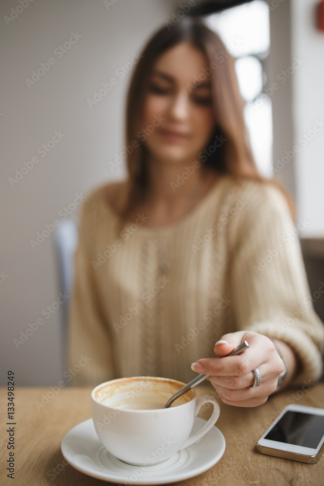 Woman stir sugar spoon in cup of cappuccino in cafe Woman stir sugar spoon in cup of cappuccino in cafe
