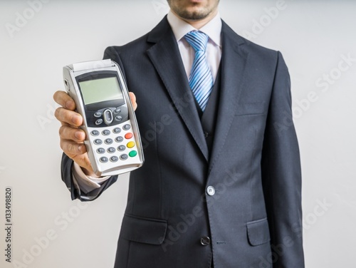 Businessman holds payment terminal in hand.