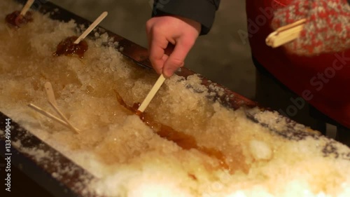 man prepares maple syrup on stick in ice-Canadian treat