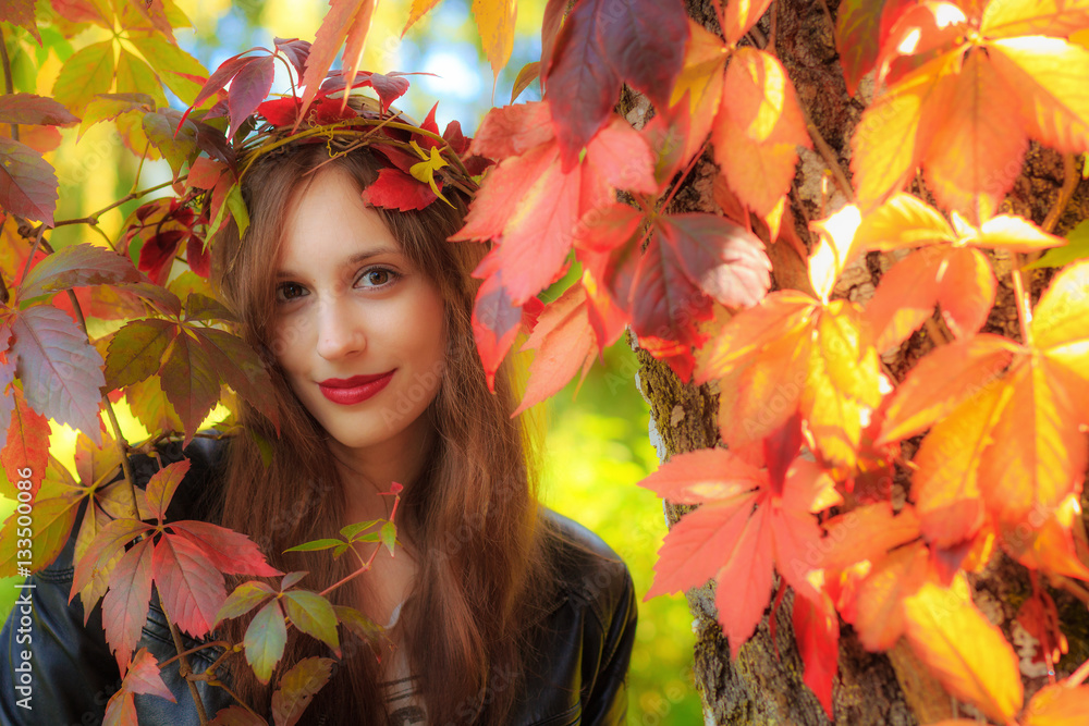 A young woman in an autumn forest with leaves in her hair