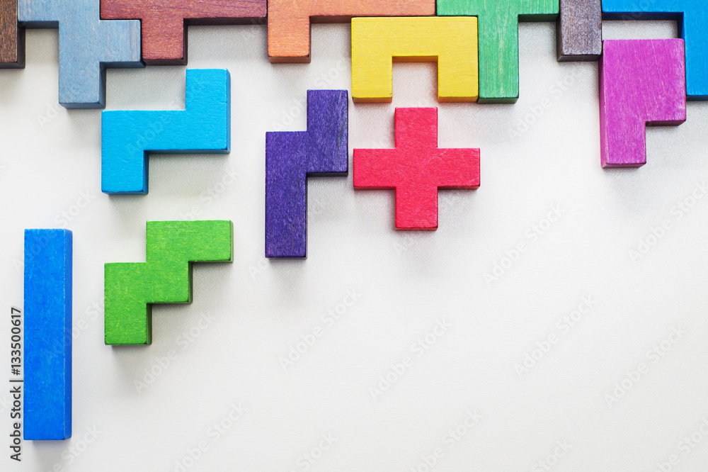 Obraz premium Different colorful shapes wooden blocks on beige background, flat lay. Geometric shapes in different colors, top view. Concept of creative, logical thinking or problem solving. Copy space.