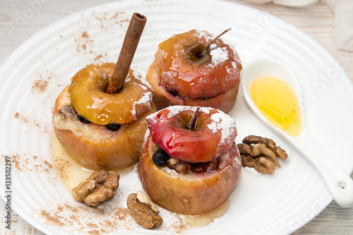 Baked apples stuffed with walnuts and honey on white plate