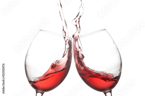 Two red wine glasses and splashing action on white background. Cheer celebration concept photo. Macro view photo.