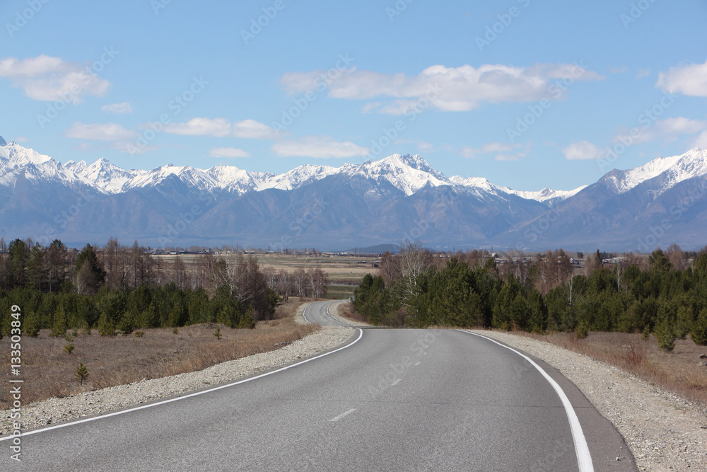 The highway among trees and the Sayan Mountains in the spring, B