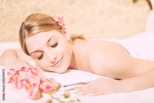Attractive woman laying on massage spa bed white background, portrait closeup