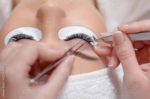 Stylist lengthening lashes for female in a beauty salon.
