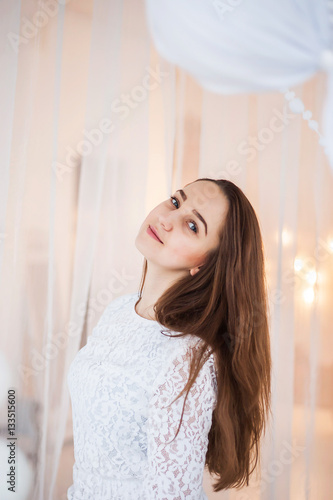 A young girl in a white dress posing on a white background