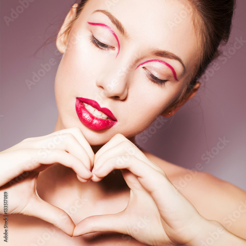 Beautiful brunette woman with red full lips and red lines on her eyelids and braid hairstyle