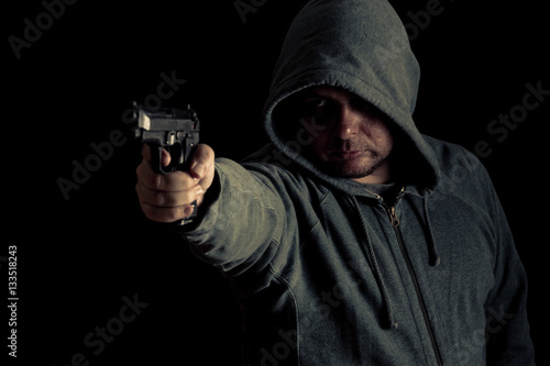 Billede på lærred Thug in hoodie points gun