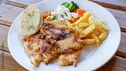 chicken steak with french fries, bread, and salad.
