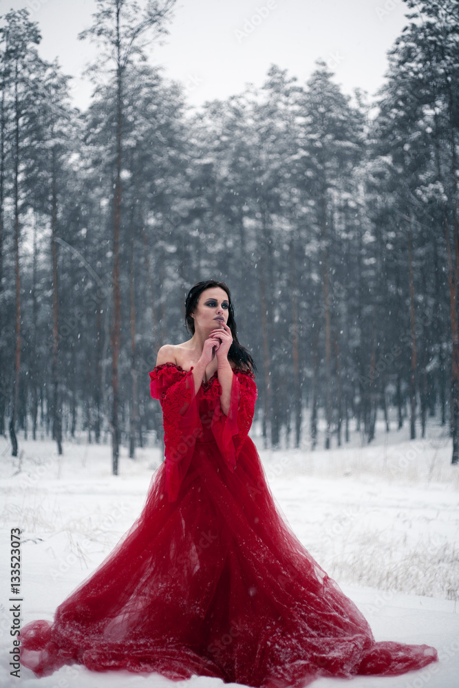Thoughtful girl in a red dress in snowy forest. Thoughtful girl in a red dress in snowy forest.