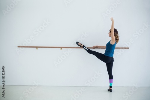 Dancer stretching on a barre while practicing dance